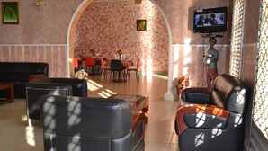 Zona d'estar àmplia amb sofà, cadires i televisió penjada a la paret.