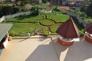 Um terraço com vista para um jardim ajardinado, incluindo um canteiro de flores circular e um caminho.