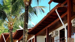 A two-story building with a balcony, stone pillars, and potted plants. - HOTELARE Hotel Brunello (Paraty)