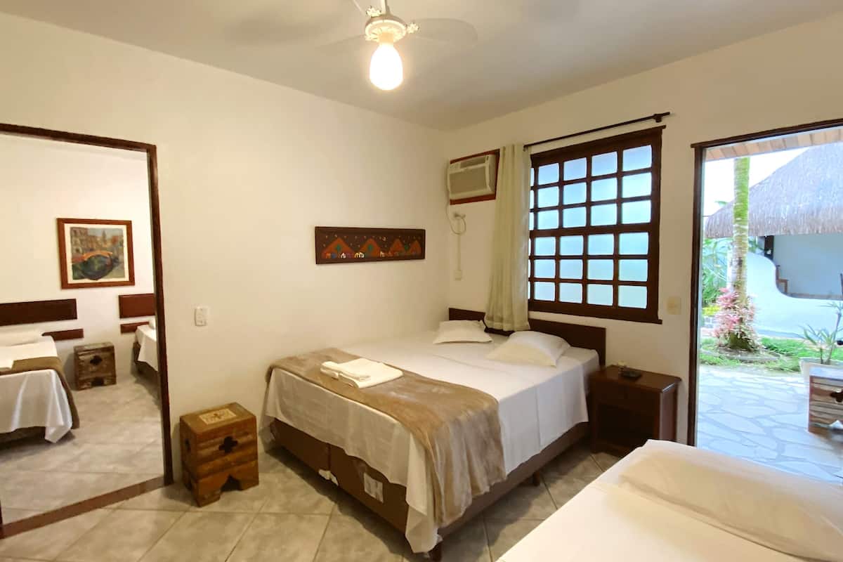 Habitación de hotel con cama, mesitas de noche, armario, espejo y ventana con vistas al exterior.