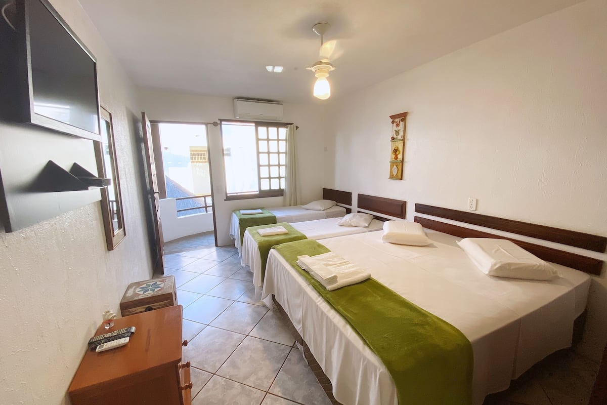 Habitación de hotel con dos camas, un escritorio, un televisor y una ventana con vistas.