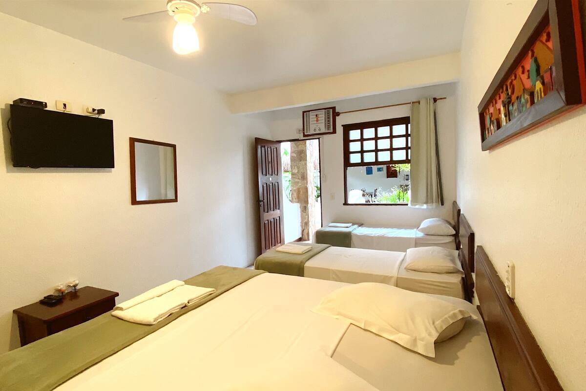 Habitación de hotel con dos camas, televisión, reloj y ventana con cortinas.