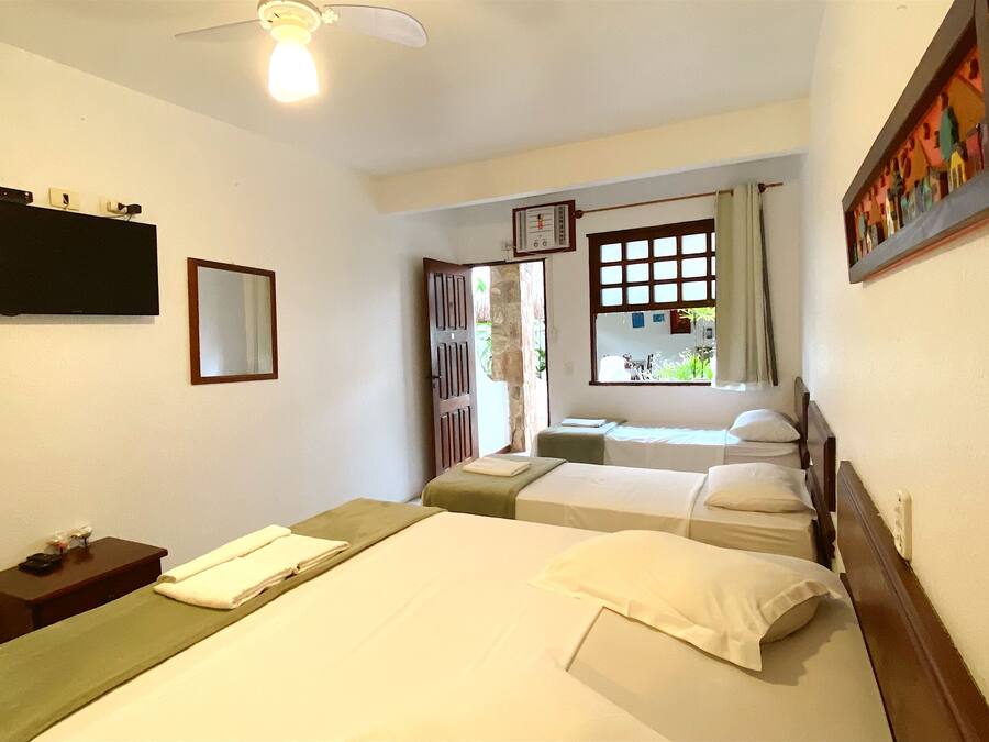 A hotel room with two beds, a TV, a clock, and a window with curtains.