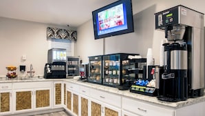 A modern kitchen with a coffee station, a television, and a display case with baked goods.