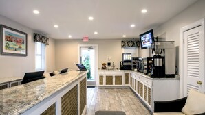 A modern kitchen with a granite countertop, white cabinetry, and a coffee machine.