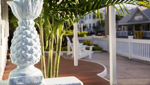 A white decorative sculpture in a garden area with a white fence and a building in the background.