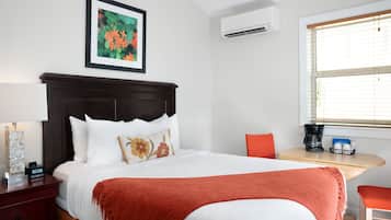 Hotelkamer met een bed, nachtkastje met lamp, koffiezetapparaat en raam met jaloezieën.