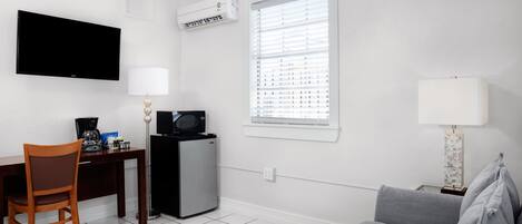 A small, clean room with a desk, chair, and a gray sofa.