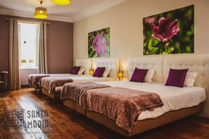A hotel room with three beds, a wooden floor, and a large window with curtains. - Santa Maria - Hostel (Funchal)