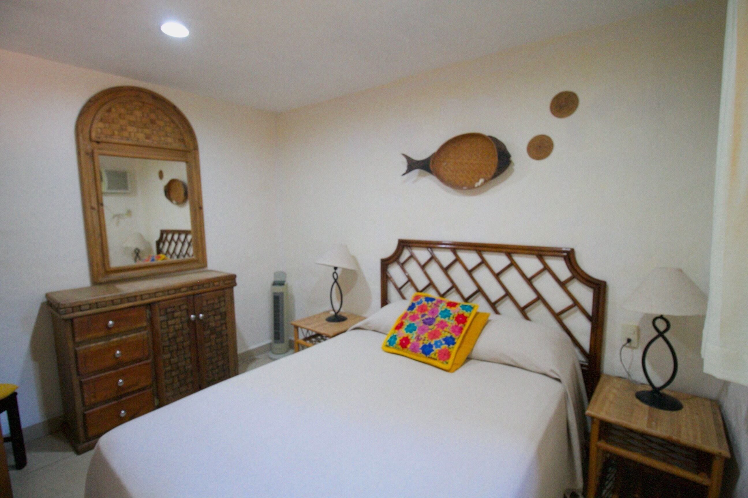 Un dormitorio con cama, cómoda, mesitas de noche y adornos en la pared.
