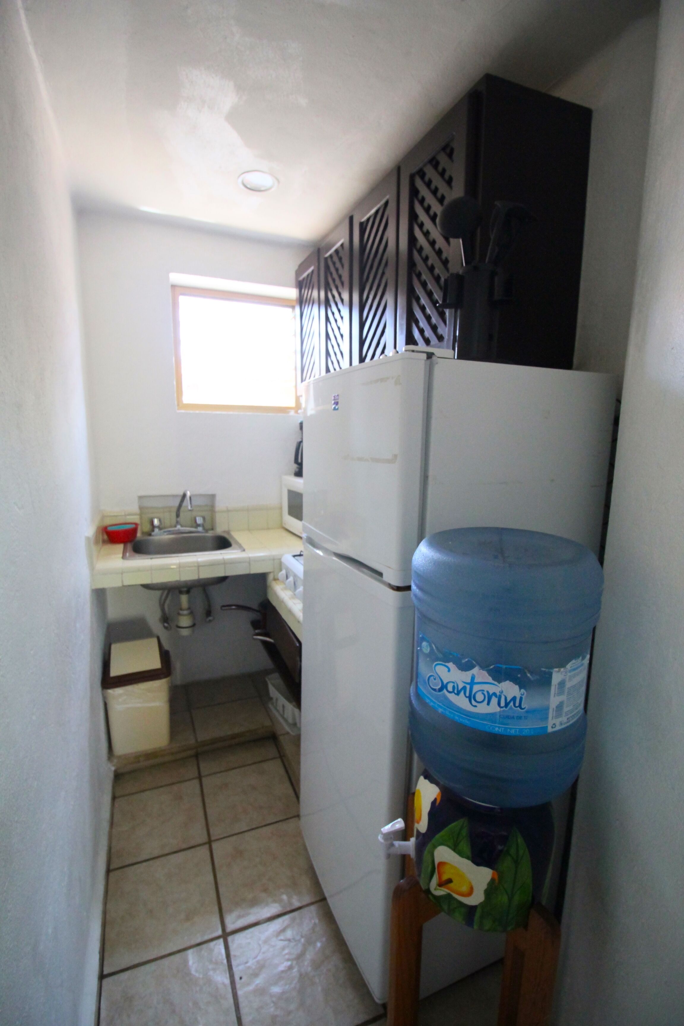 A compact kitchen with a sink, a microwave, a refrigerator, and a water dispenser.