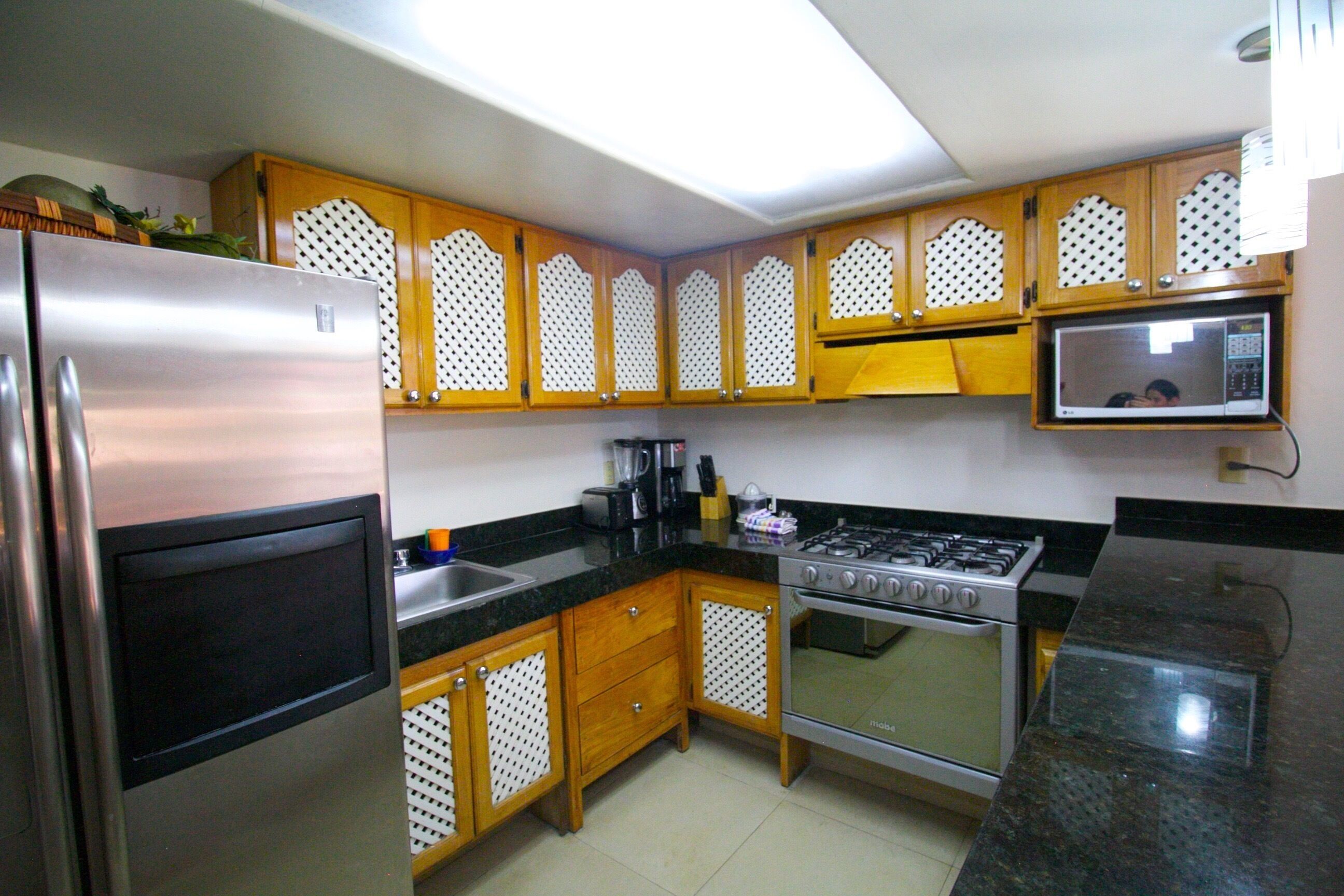 A kitchen with wooden cabinets, a stainless steel refrigerator, a gas stove, and a microwave.