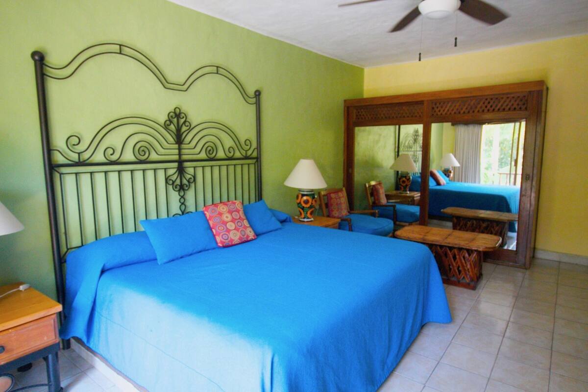 Una habitación con cama, escritorio, silla, mesa y ventilador de techo.