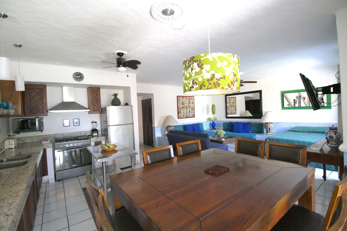 Una cocina amplia con zona de comedor, ventilador de techo y un ventanal grande.