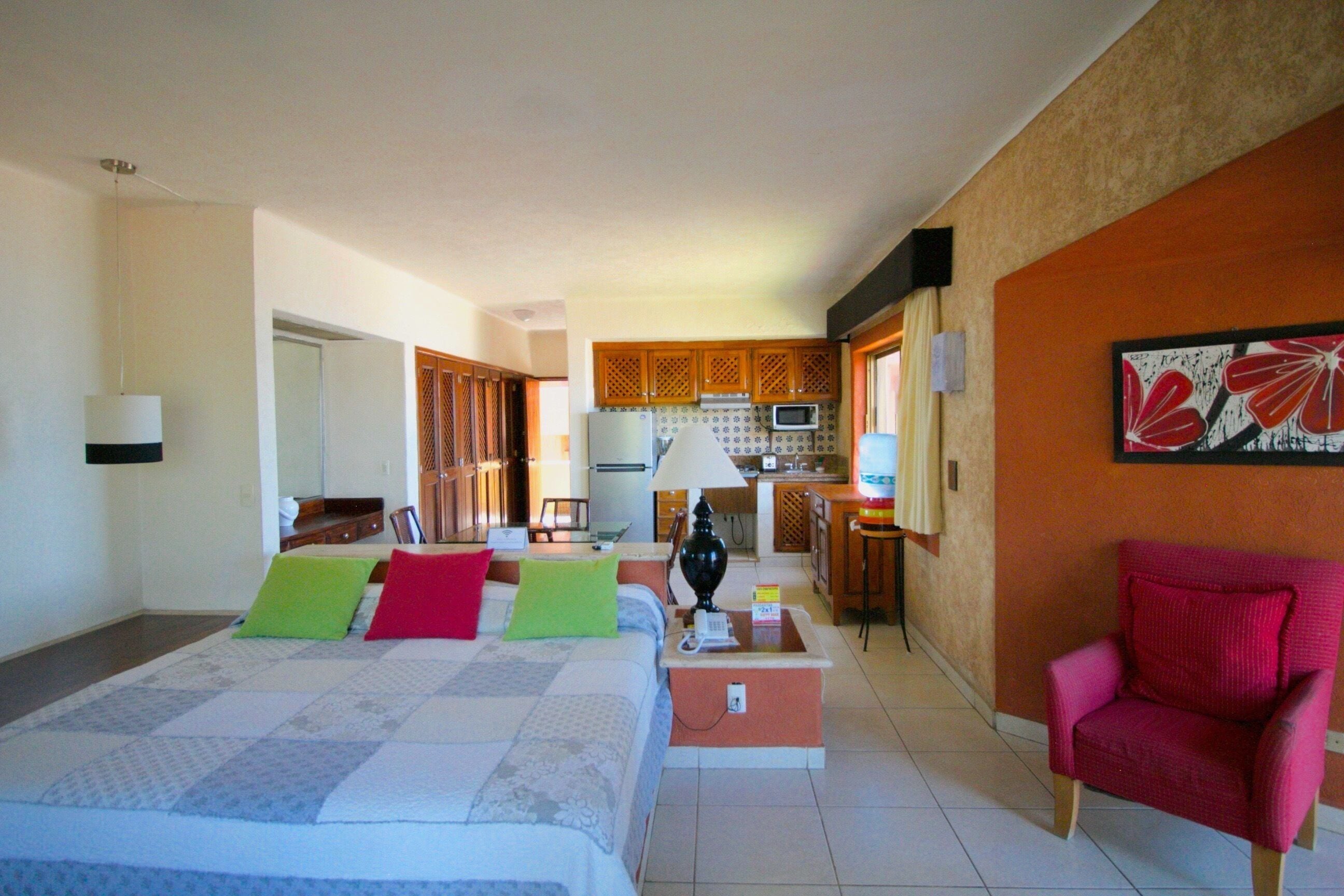 Een hotelkamer met een bed, een stoel, een bureau en een kitchenette.