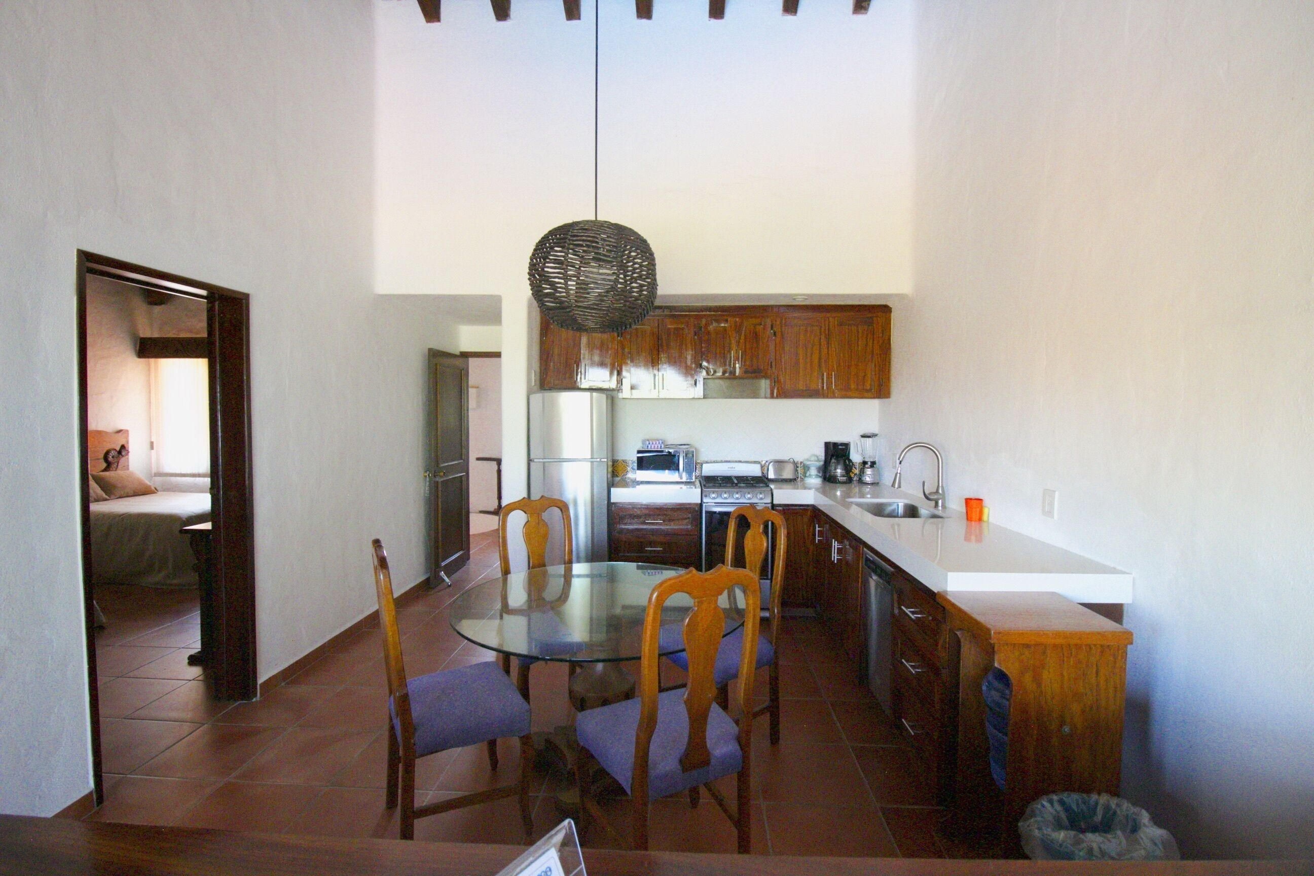 A compact kitchen with wooden cabinets, a round glass table, and four chairs.