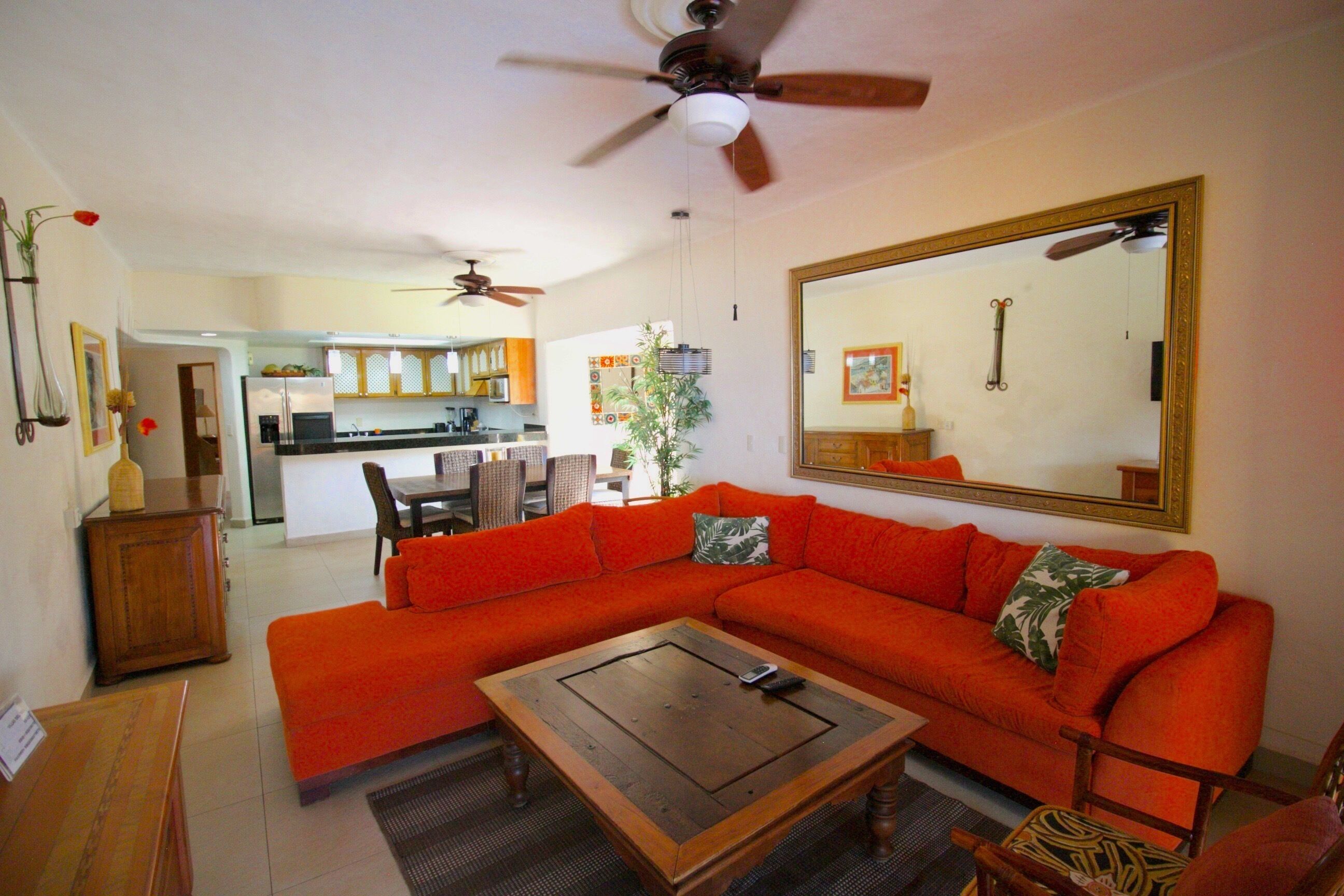 A living room with a large sectional sofa, a coffee table, and a dining area in the background.