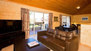 Ein Wohnzimmer mit Ledersofa, Fernseher und Essbereich mit Tisch und Stühlen.