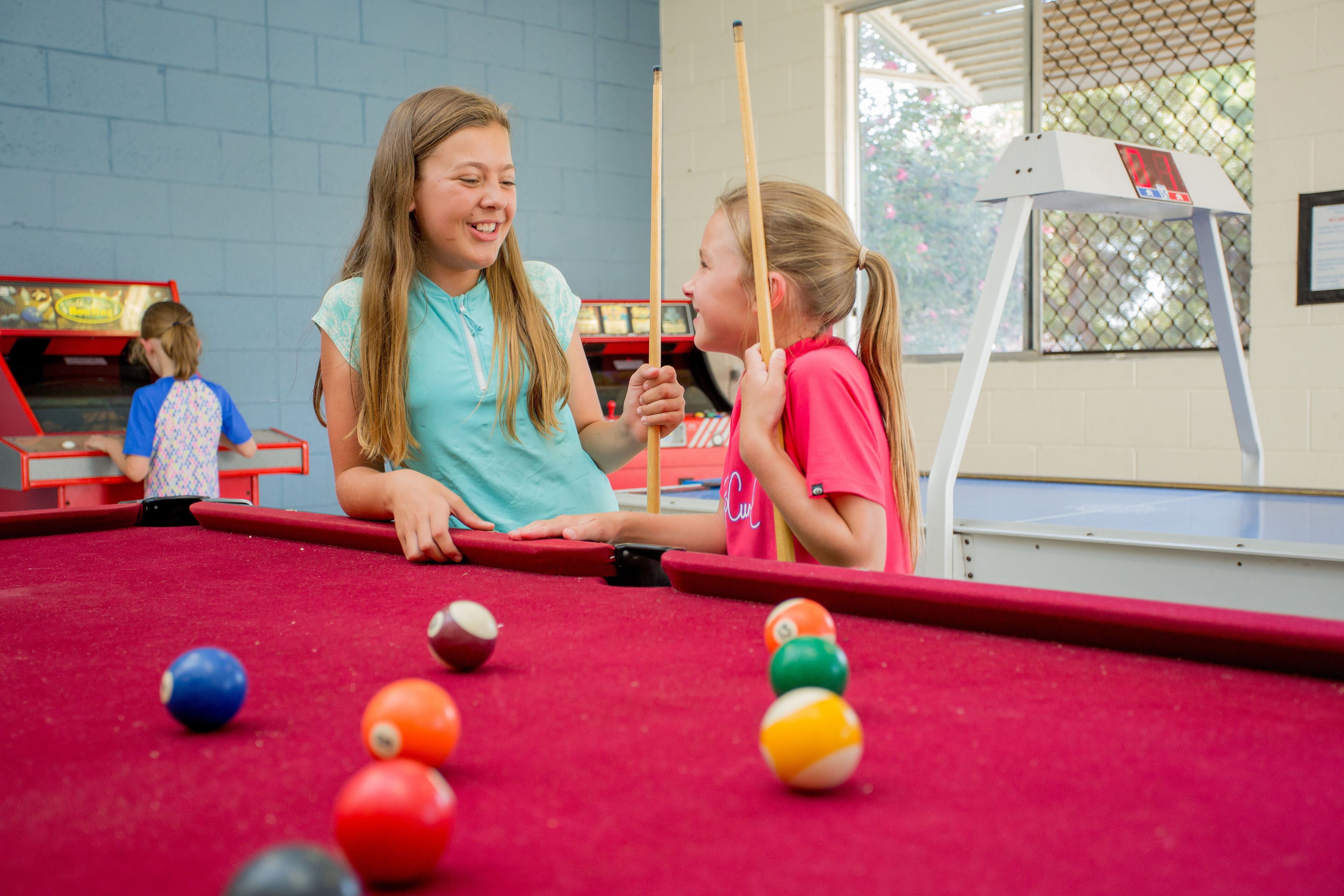 A pool table with balls and two people playing.