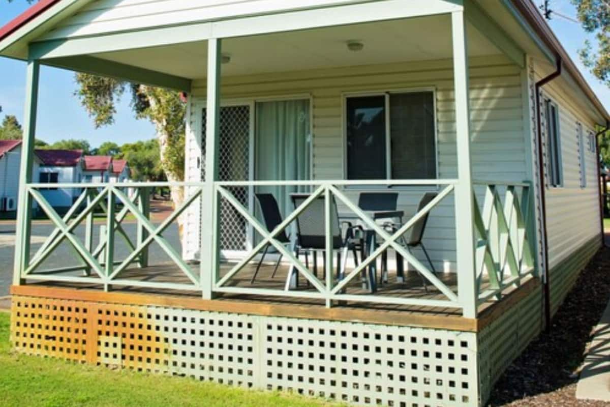 Une maison mobile de plain-pied avec une véranda, une petite table et des chaises.