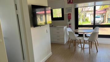 Una cucina moderna con mobili bianchi, una TV a schermo piatto e un'area pranzo con sedie bianche e un tavolo rotondo.