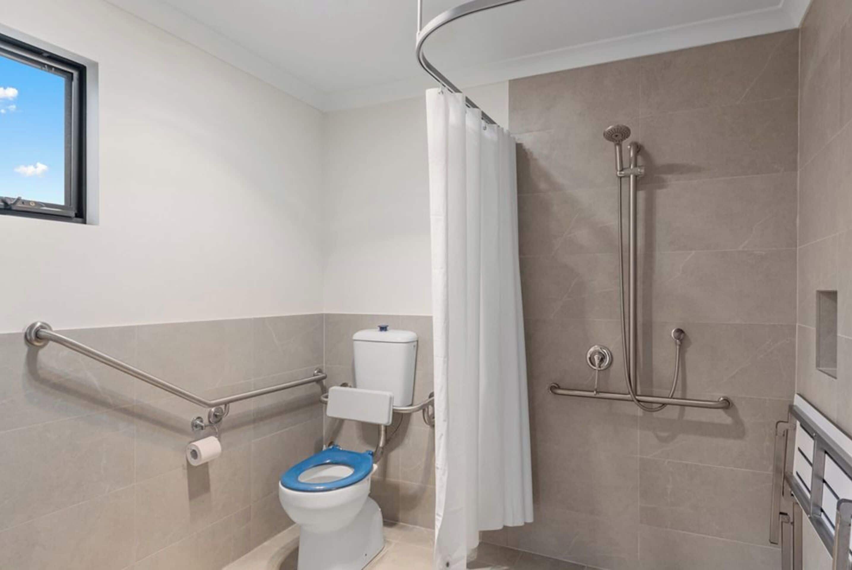 A bathroom with a toilet, shower, and grab bars.