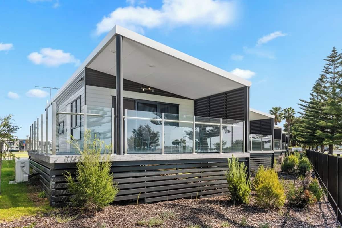 Une maison moderne dotée de grandes fenêtres, d’un toit plat et d’un design minimaliste.