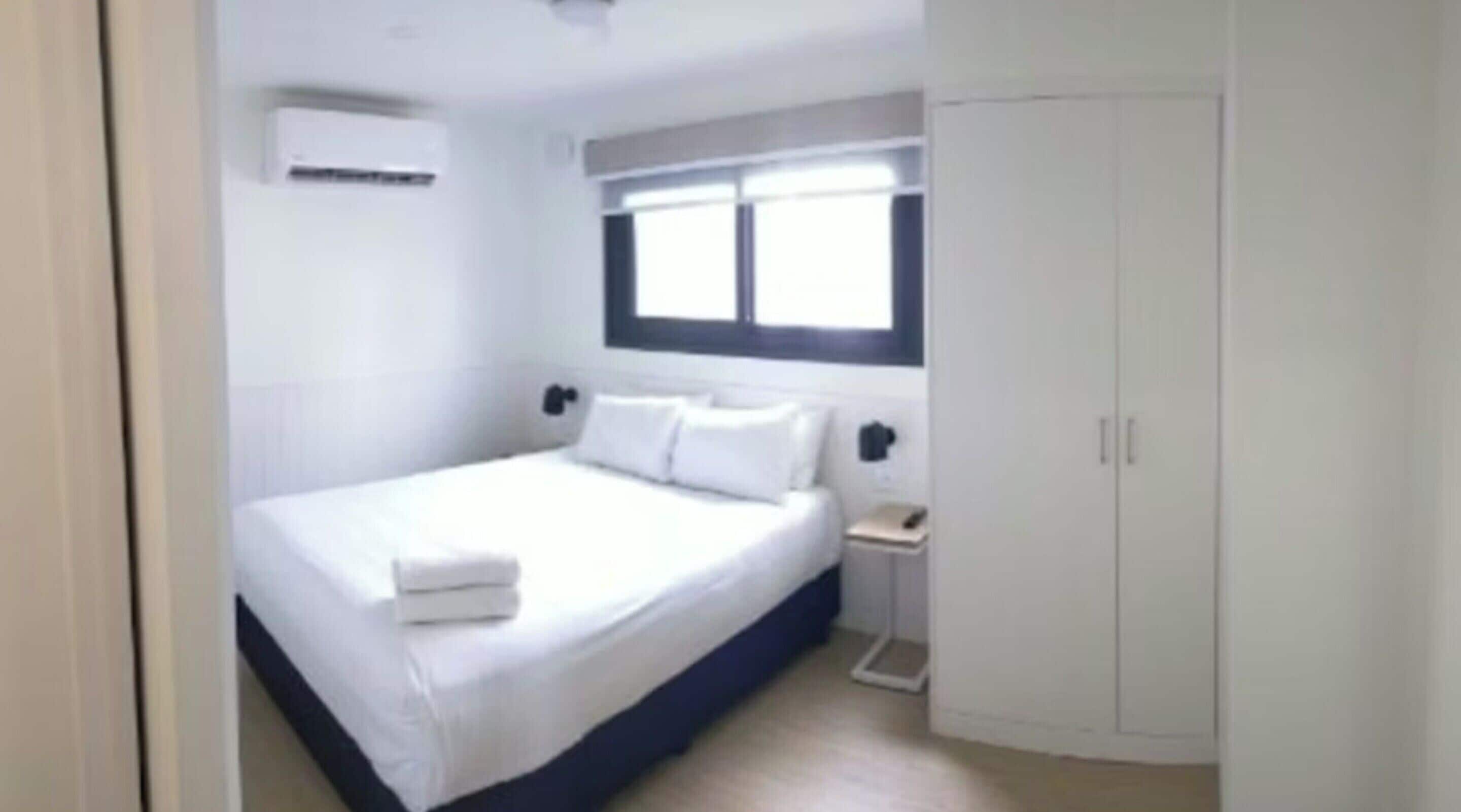 Une chambre à coucher avec un lit, une armoire, une fenêtre et une table de chevet.