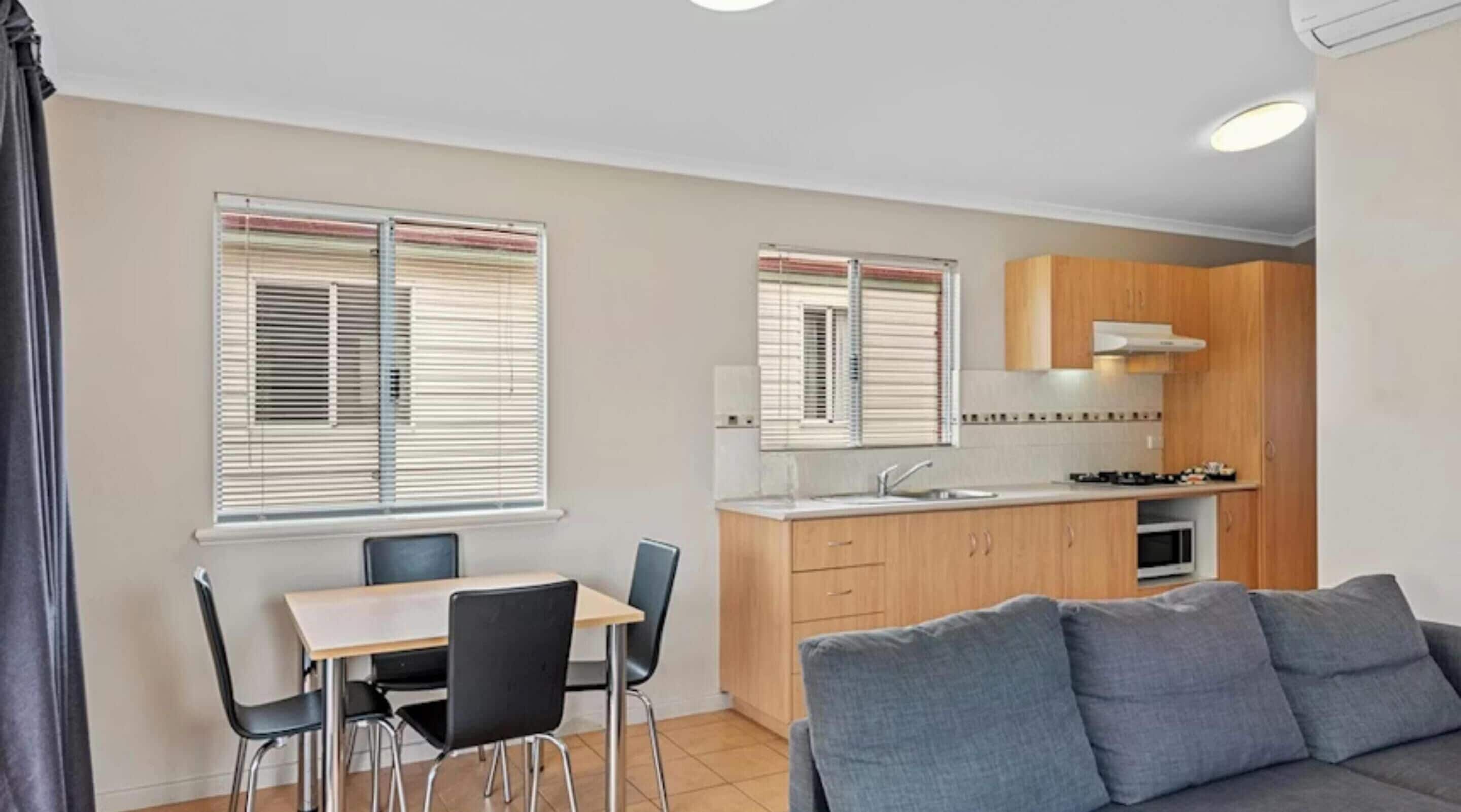 A compact living space with a dining area, kitchenette, and a sofa.