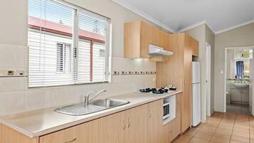 A modern kitchen with a large window, built-in cabinets, a stainless steel sink, and a refrigerator.