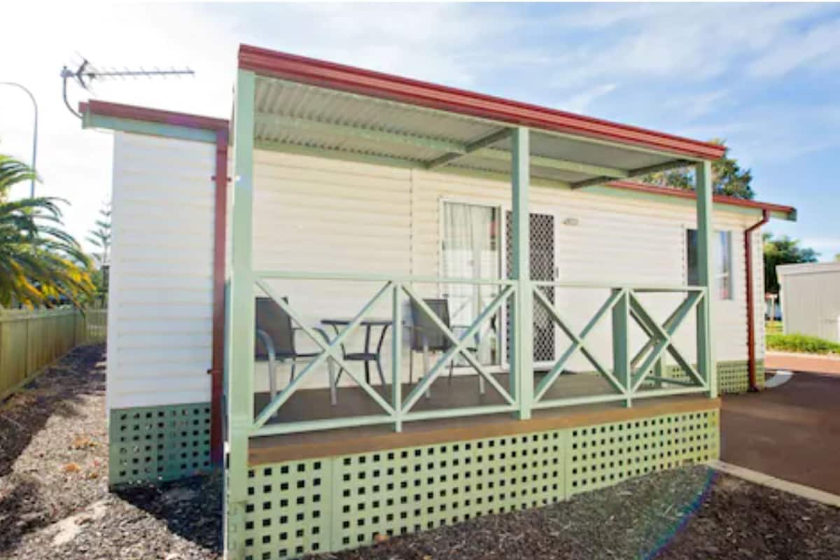 Une maison mobile dotée d’un porche couvert, d’un petit espace patio et d’une cour clôturée.