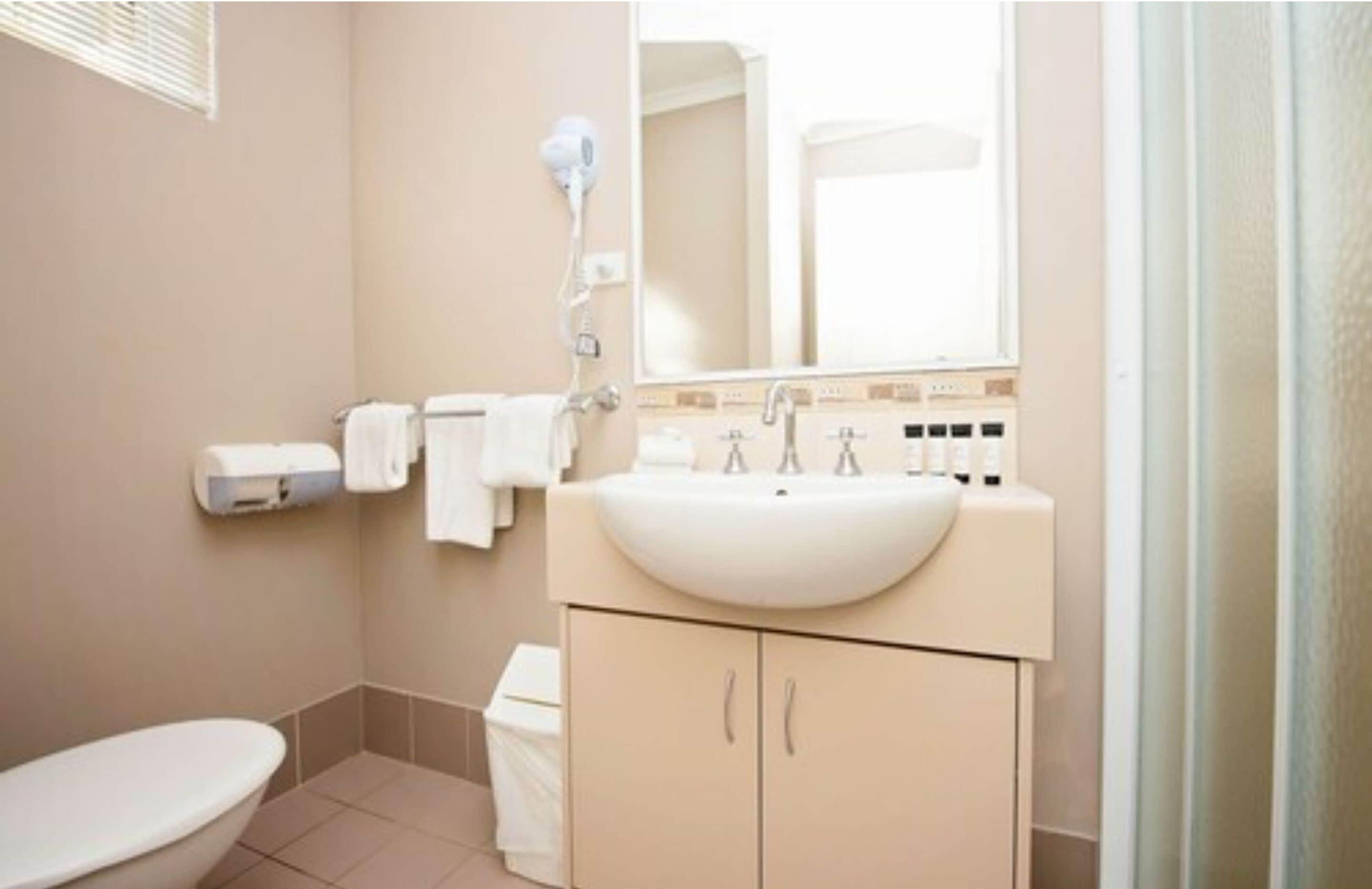 A bathroom with a toilet, sink, and shower.