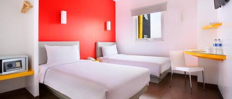 A hotel room with two beds, a desk, a chair, a TV, and a window with a view of a building.