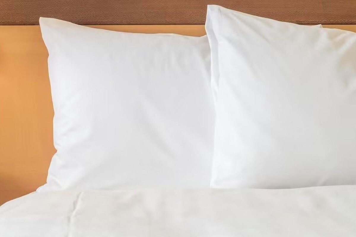 Una cama con ropa de cama blanca y almohadas.