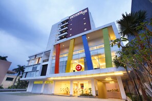A modern hotel with a prominent 'a' logo, multiple floors, and a well-lit entrance. - Amaris Hotel Pakuan Bogor (Bogor)