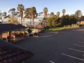 Un estacionamiento con área de lavado de autos techada, un edificio de techo a dos aguas y vista al mar.