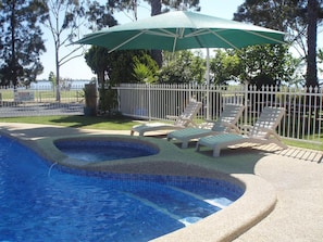 A swimming pool with a tiled edge, surrounded by a white fence and a green umbrella. - Lakeview Motel (Yarrawonga)