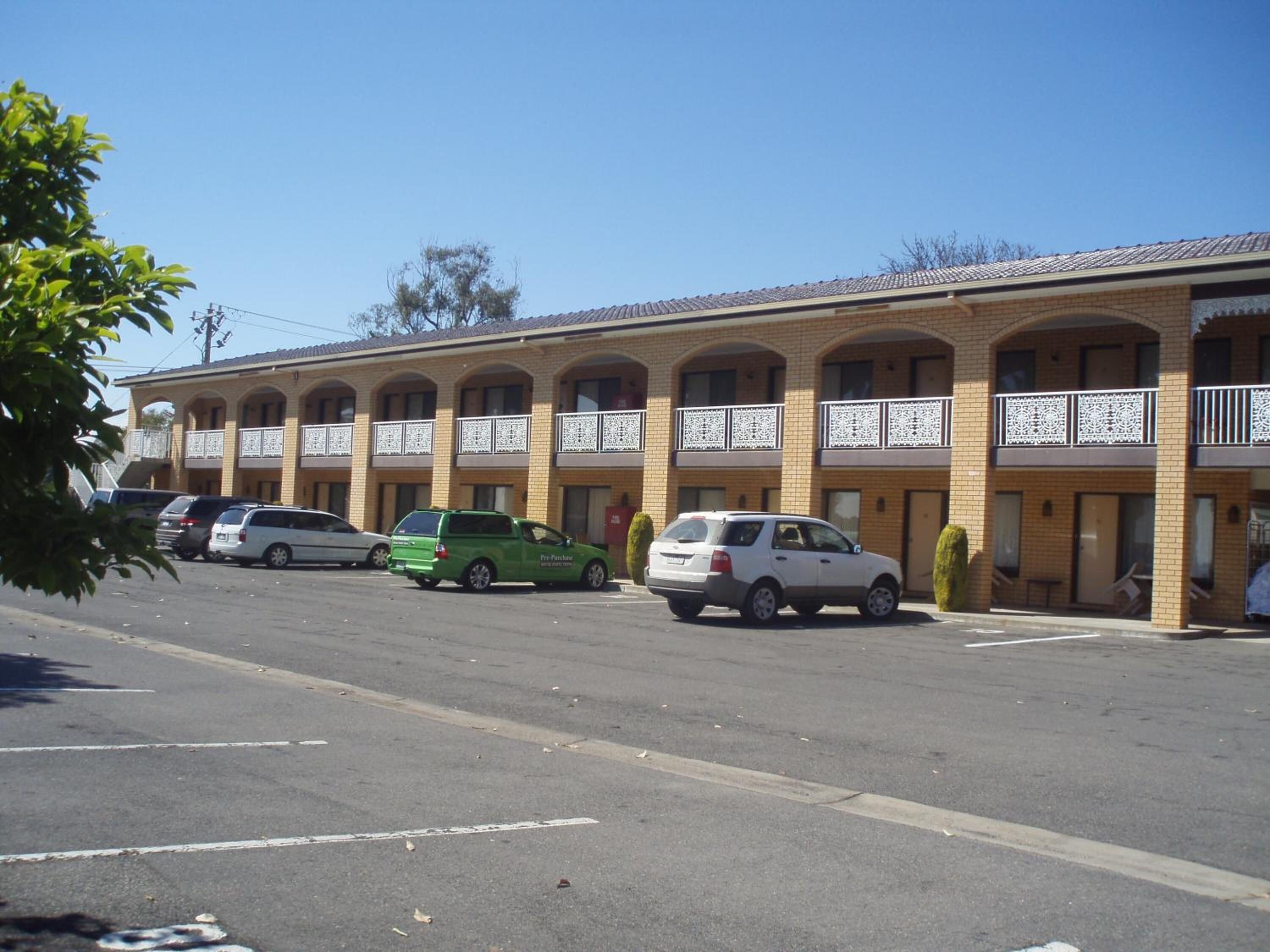 A motel with multiple rooms, a parking lot, and a clear sky.