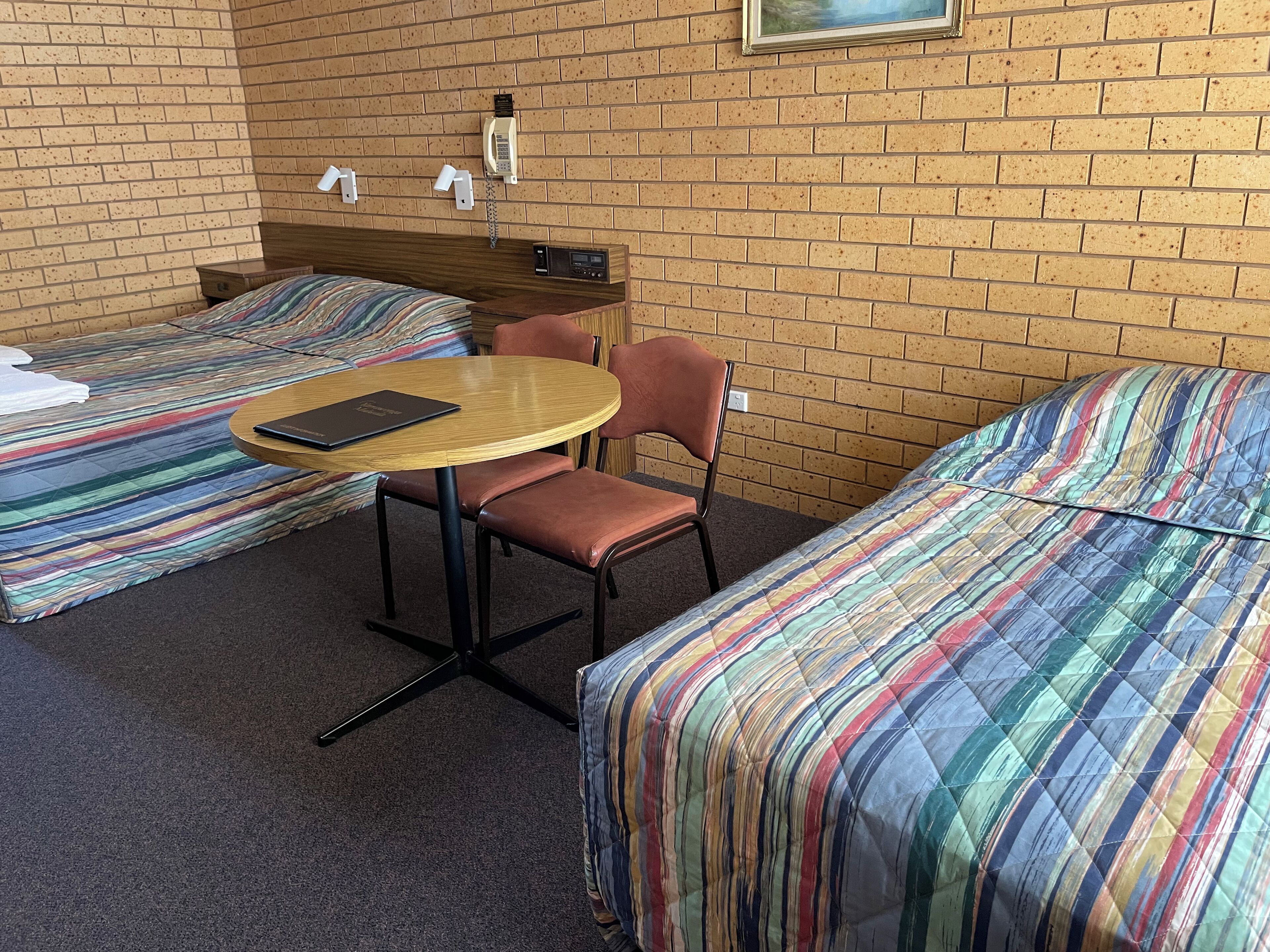 A room with two single beds, a round wooden table, and a single chair.