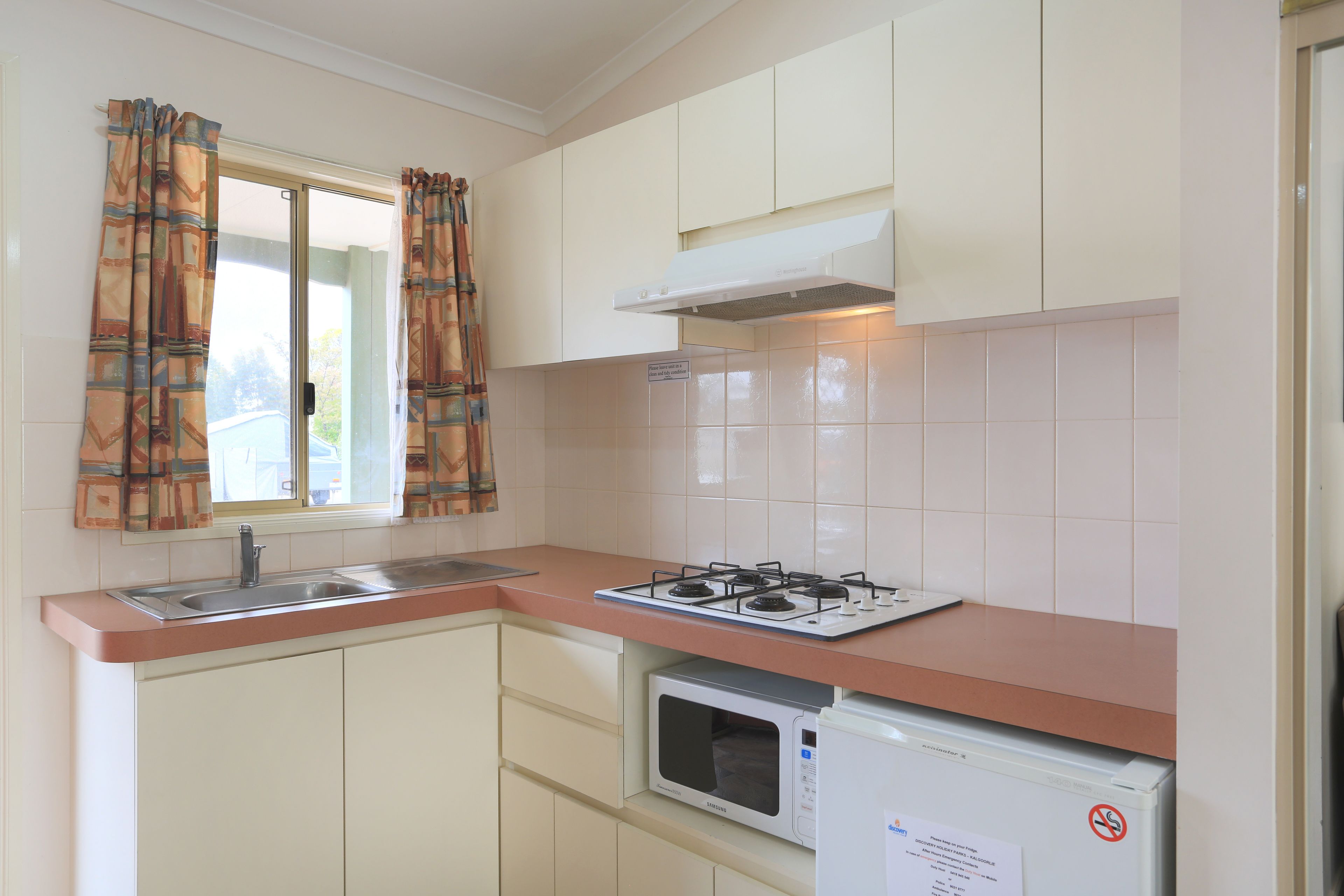 A compact kitchen with a gas stove, microwave, and a sink.
