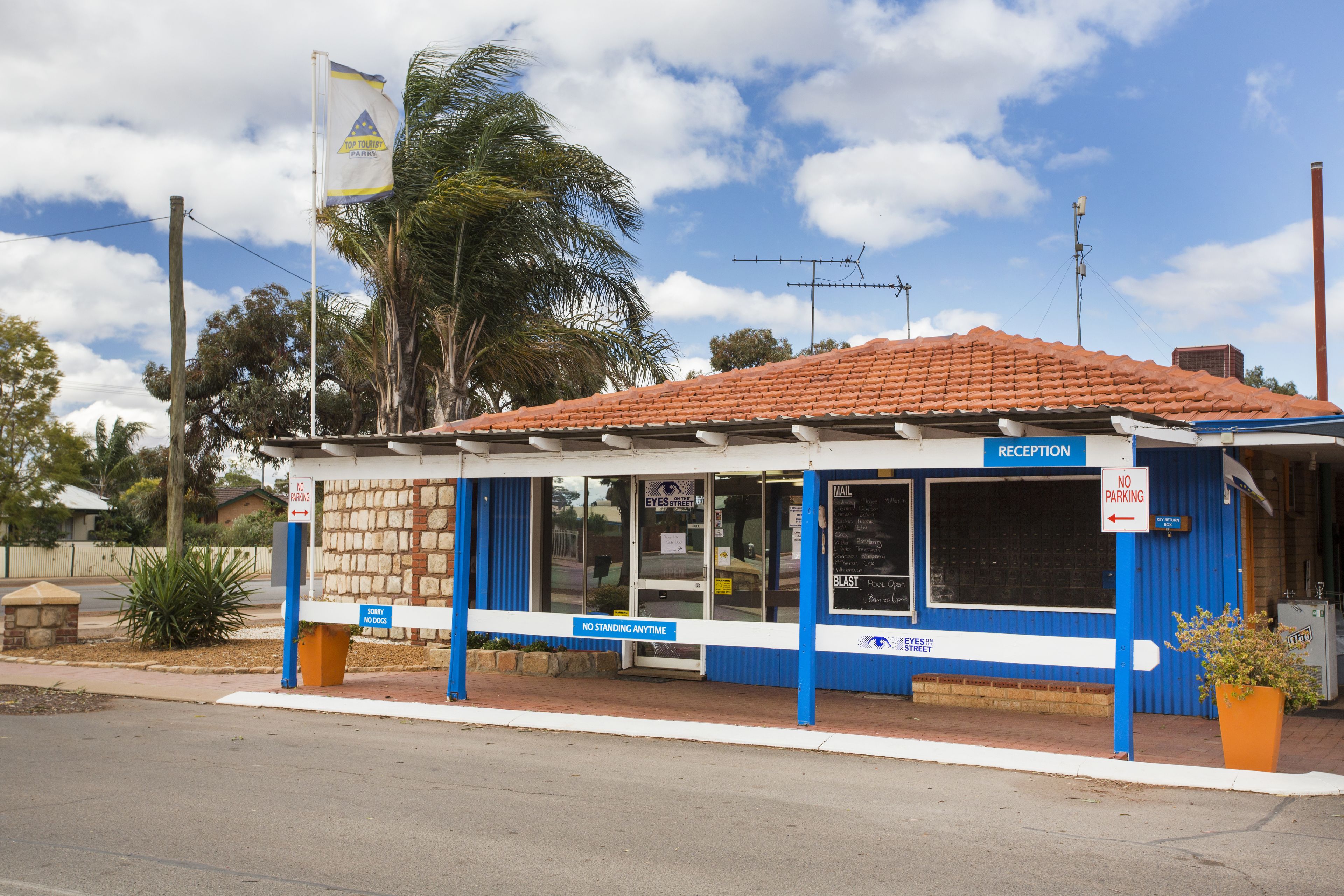 Un área de recepción con un cartel que indica prohibido permanecer de pie en todo momento, un mostrador de recepción y un letrero de no estacionamiento.