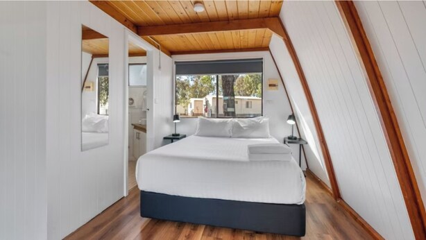 A bedroom with a bed, wooden ceiling, and a window. - Discovery Parks - Kalgoorlie Goldfields (Boulder)