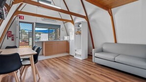 A modern interior with a dining area, sofa, and kitchen. - Discovery Parks - Kalgoorlie Goldfields (Boulder)