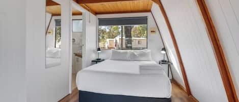 A bedroom with a bed, wooden ceiling, and a window.