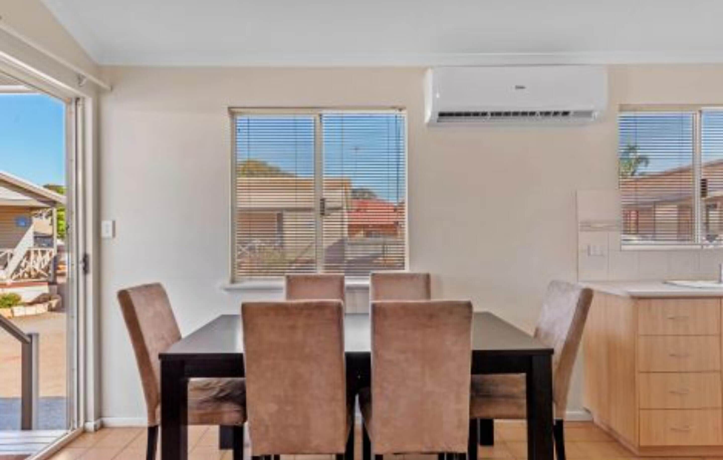 A dining area with a table and chairs, a kitchen with cabinets, and a sliding glass door leading to an outdoor area.