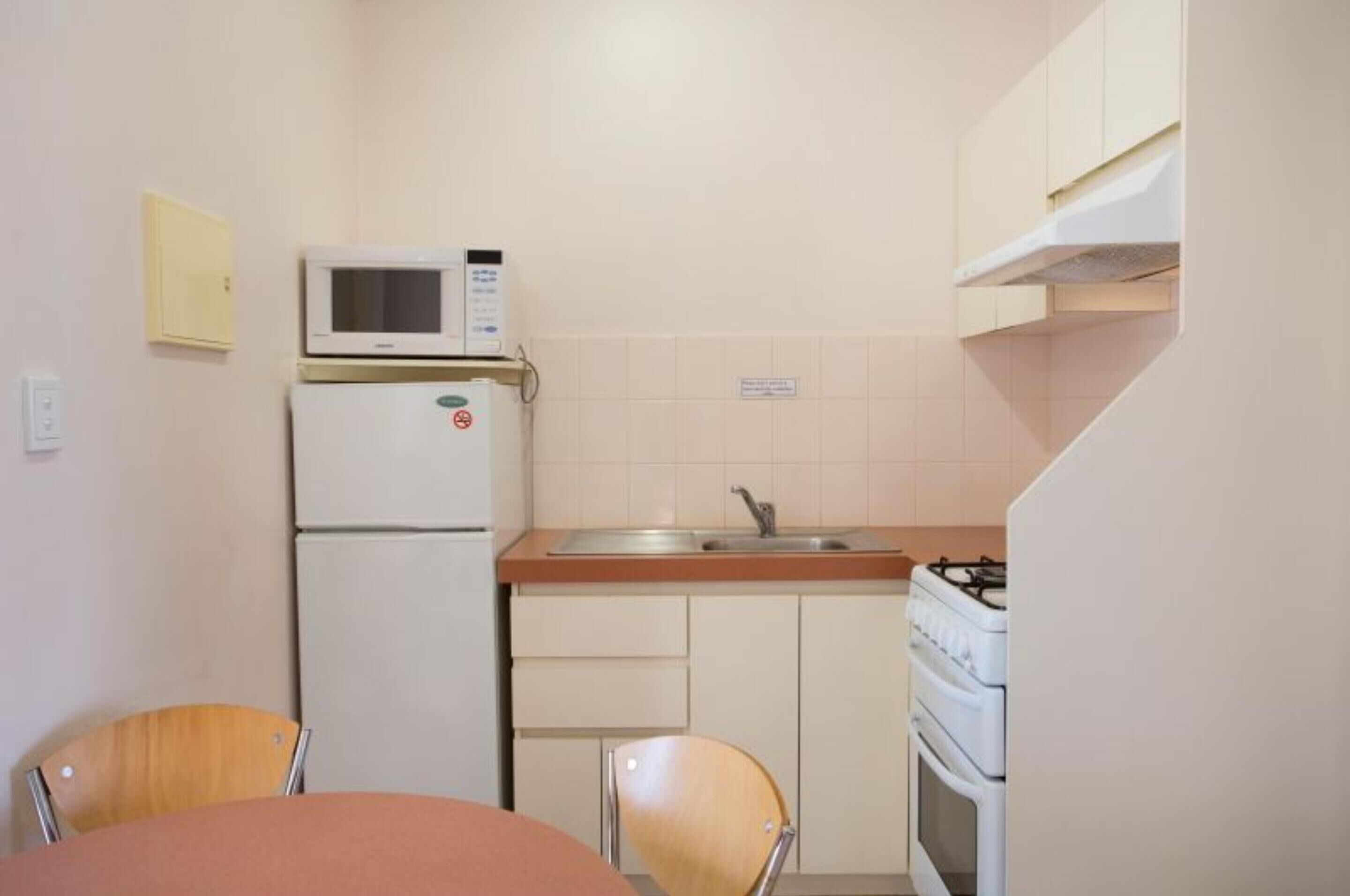 A compact kitchen with a microwave, refrigerator, sink, and stove.