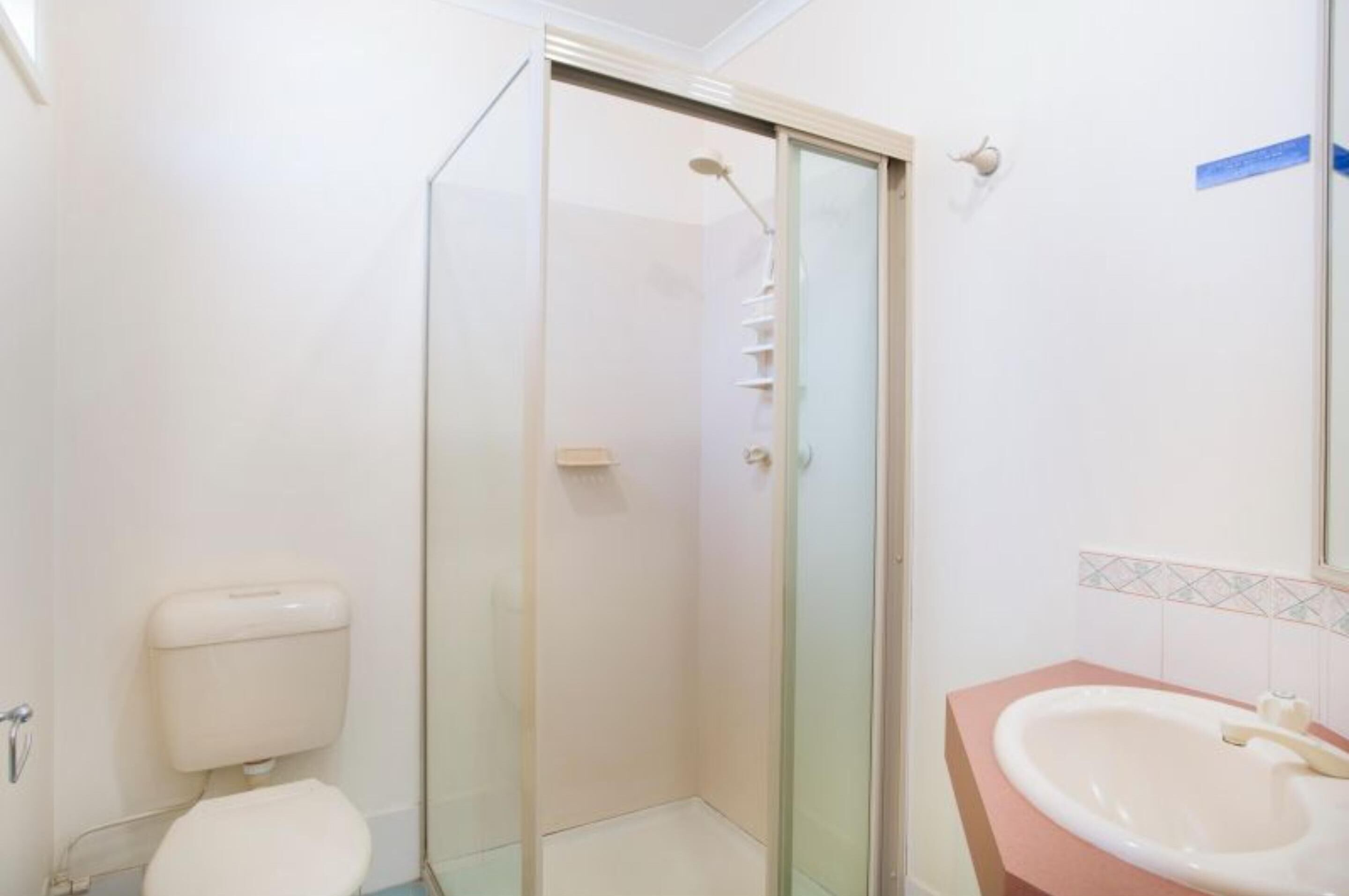 Un baño con inodoro, ducha de vidrio y lavamanos con espejo.