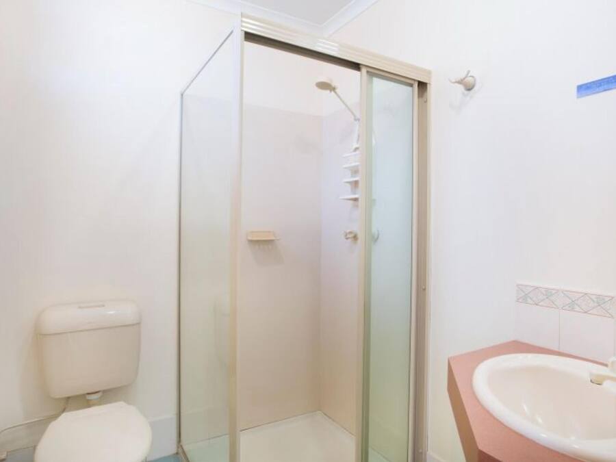 Un baño con inodoro, ducha de vidrio y lavamanos con espejo.