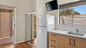 A modern kitchen with a built-in refrigerator, a window with a view of palm trees, and a sliding glass door leading to an outdoor area. - Discovery Parks - Kalgoorlie Goldfields (Boulder)