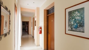 A hotel hallway with a fire extinguisher, a framed painting, and a door. - Hotel Greco (Milan)
